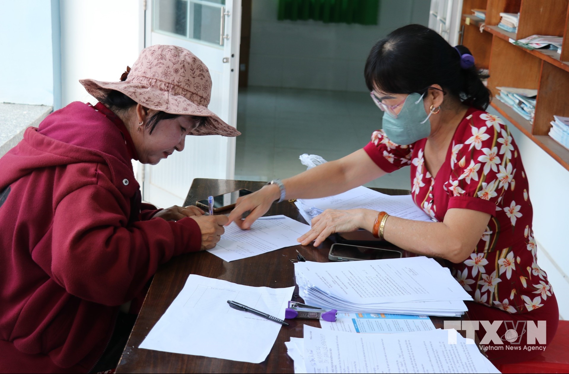 Cán bộ ấp Hòa Lạc Trung, xã Bình Ninh, tỉnh Đồng Tháp, hỗ trợ người dân làm thủ tục khai báo thông tin sức khỏe. (Ảnh: Hữu Chí/TTXVN)